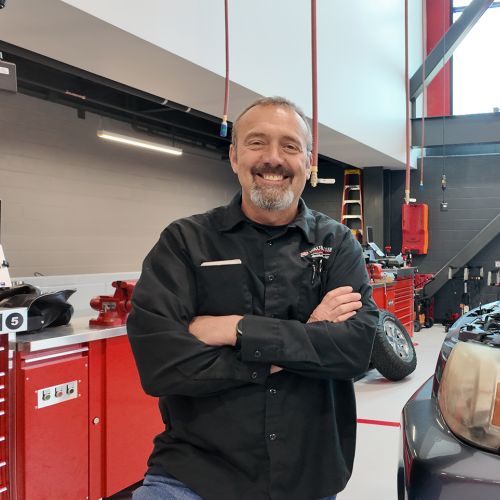 Rick Verhaagen standing in front of a car with hood open, in the Technical Education Center