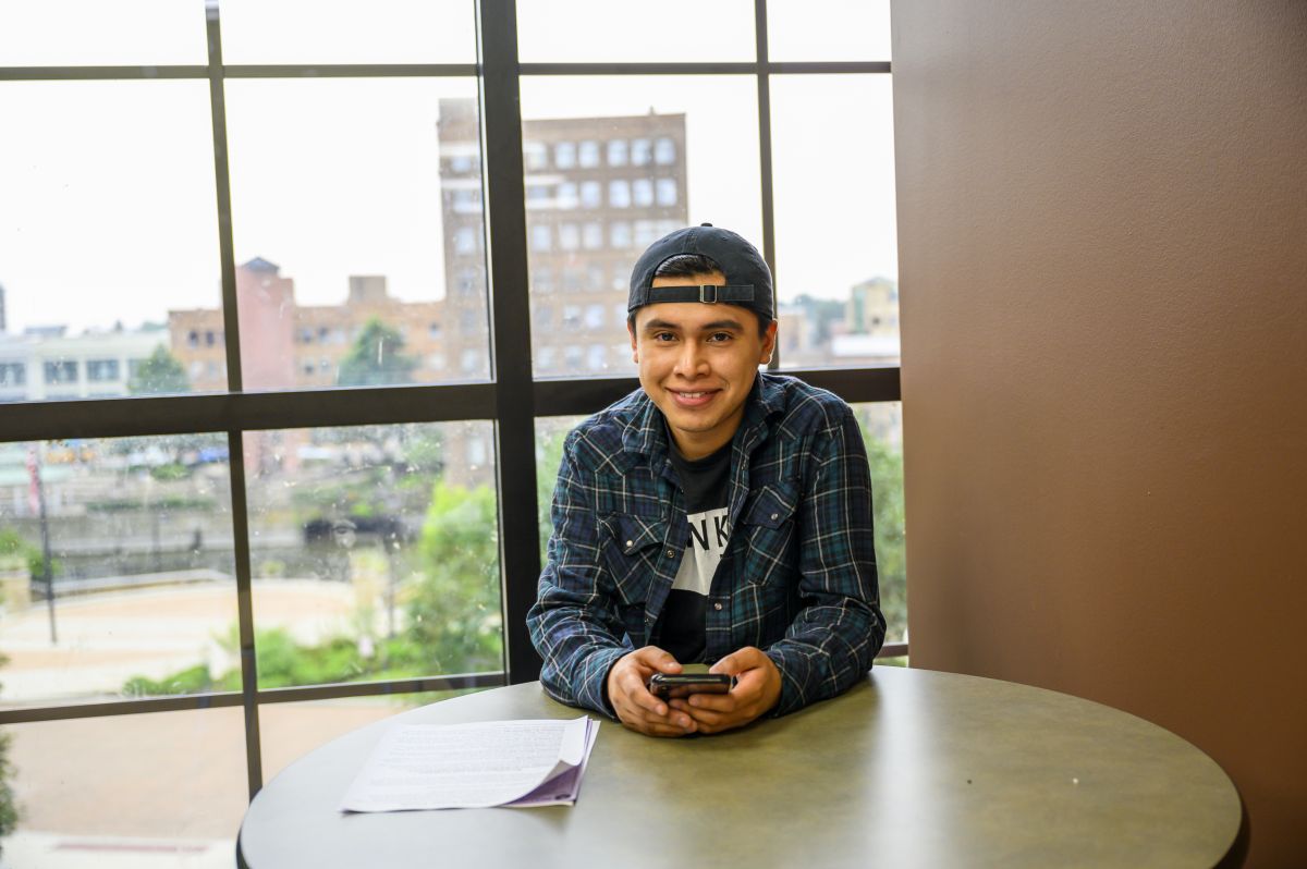 male student on phone in front of window overlooking aurora downtown