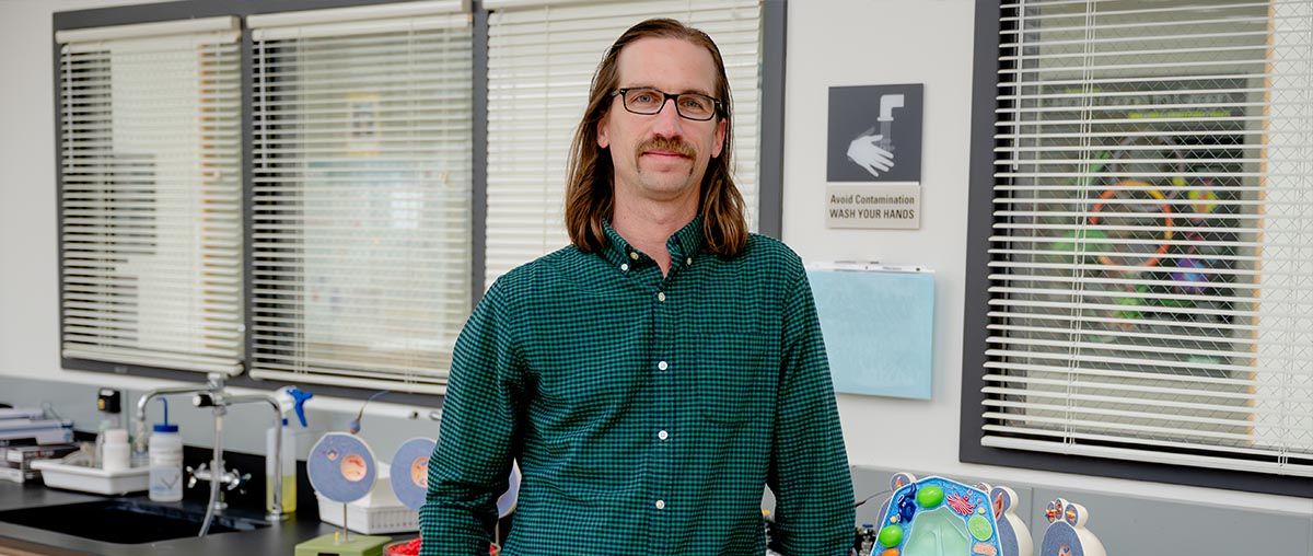 Dr. Evan Thomas - Assistant Professor of Biology standing in a lab