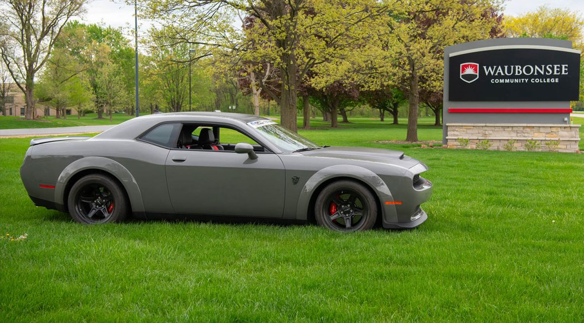 Dodge Challenger Demon parked in grass in front of Waubonsee sign