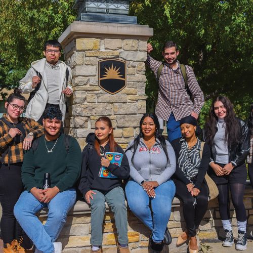 Group of students in front of pillar outside in fall