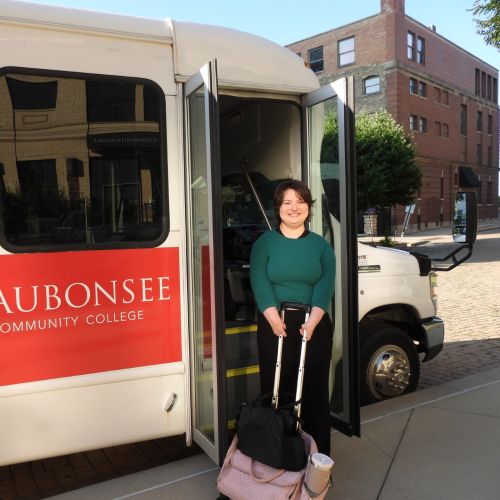 Krystal Donnelley posing in front of Waubonsee shuttle bus