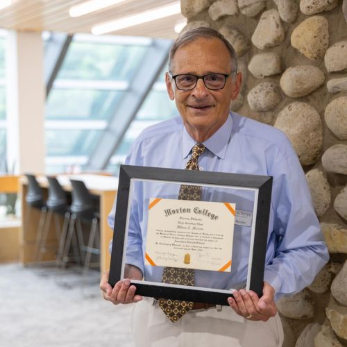 Dr. Bill Marzano, Interim Assistant Dean, stands with his Morton College diploma