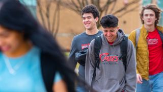 Group shot of students walking outside on campus in spring