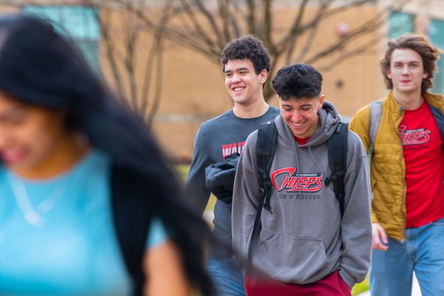 Group shot of students walking outside on campus in spring